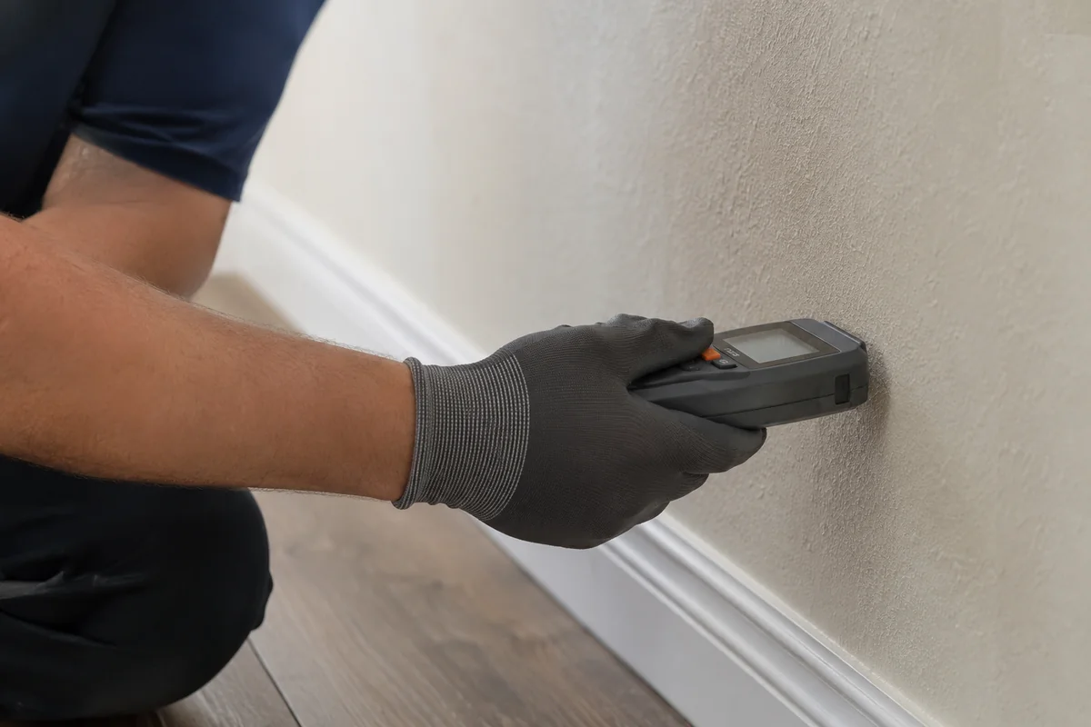 A technician checking a wall with a moisture meter